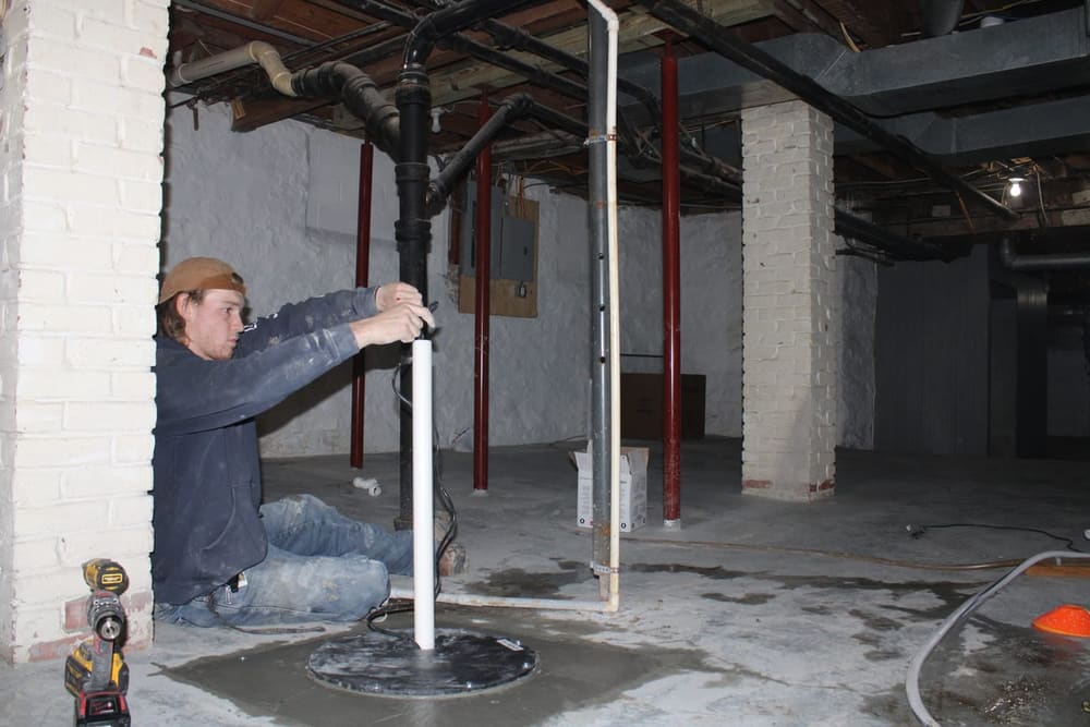 Sump pump discharge line being installed in a basement floor